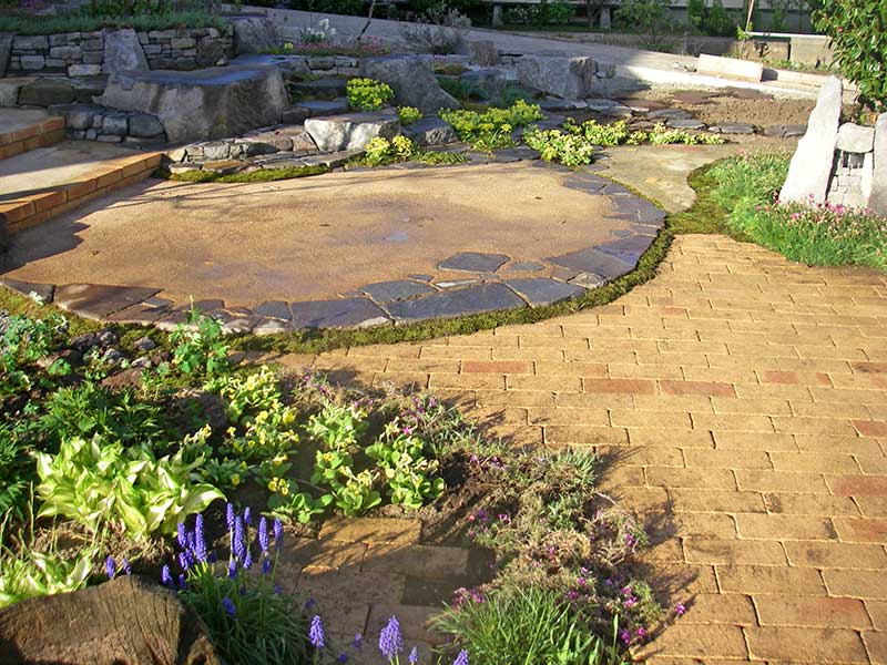 石積み花壇と形を呼応させ、園路へと繋ぐ円形テラス